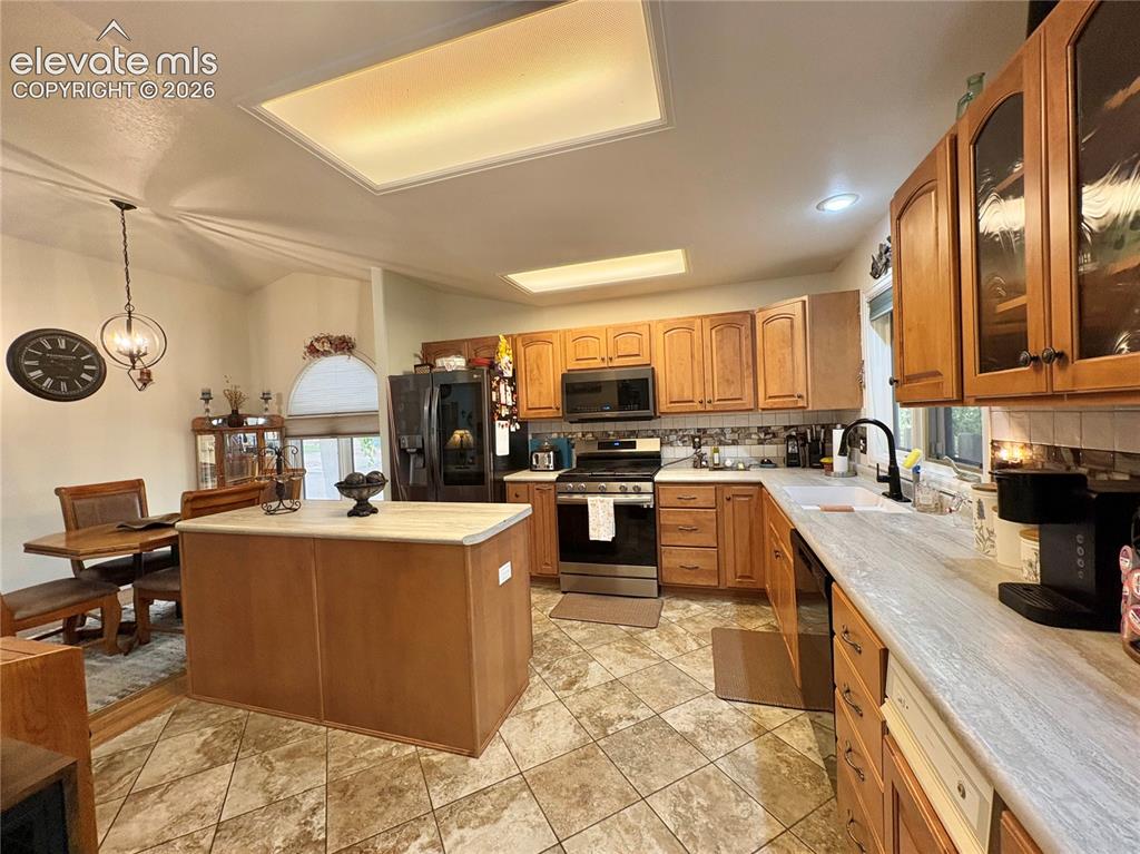 Image 12 of 28: Kitchen featuring wood-finish cabinetry, stainless steel appliances, a cent