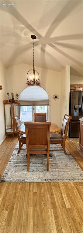 Image 13 of 28: Vaulted ceiling featuring a decorative pendant light, wood-finish flooring,