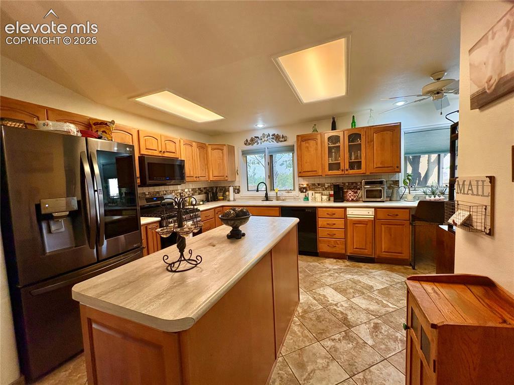 Image 14 of 28: Kitchen featuring wood cabinetry, stainless steel appliances, a center isla