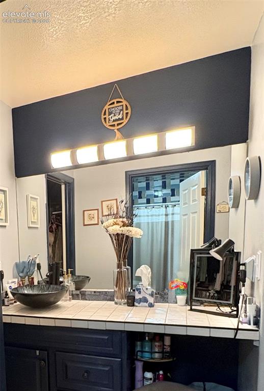 Image 17 of 28: Custom vanity with a vessel sink, tile countertop, and integrated storage