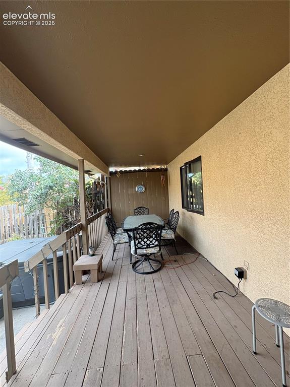 Image 27 of 28: Covered outdoor deck with wood-finish flooring