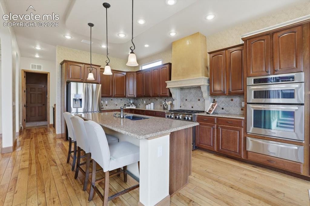 Image 10 of 32: Gourmet Kitchen with Wood Flooring, Island, Granite Countertops, Deco Tile