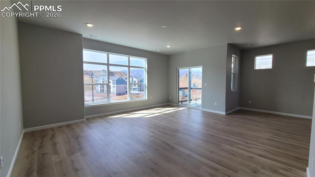 Image 8 of 24: Living Room with LVP flooring, LED lighting, walk-out to deck, and an abund