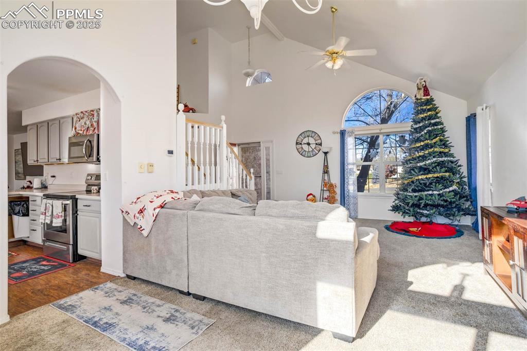 Image 11 of 27: Living room featuring high vaulted ceiling, a ceiling fan, arched walkways,