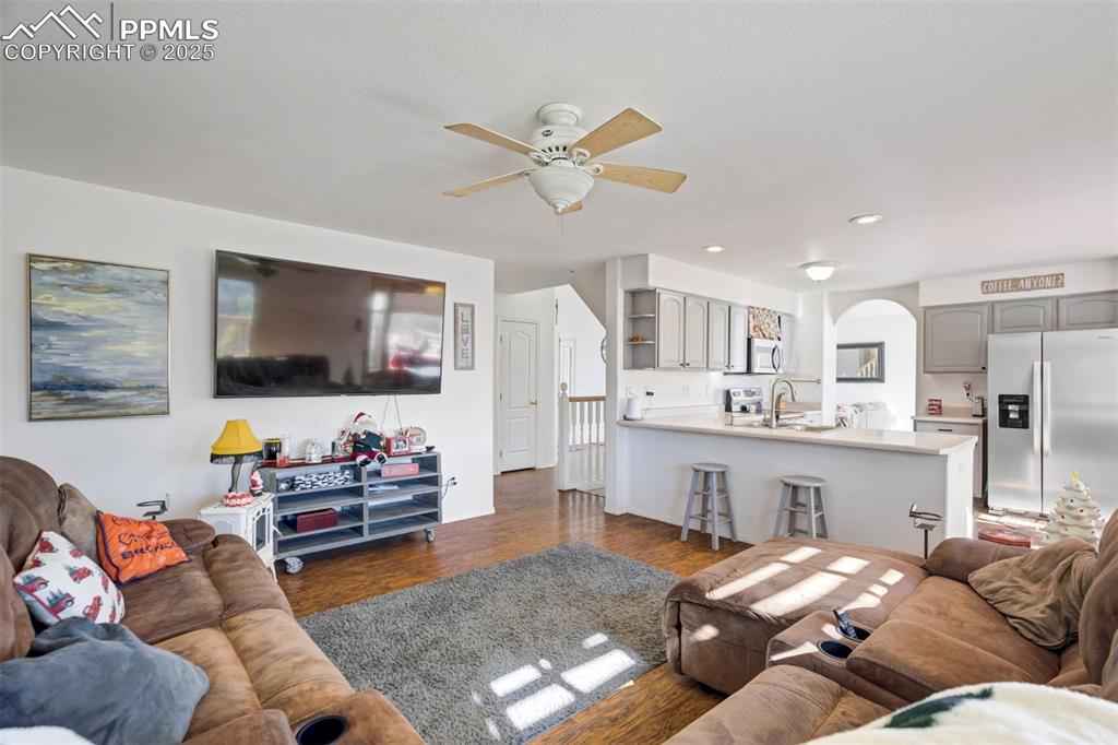 Image 15 of 27: Living area with wood finished floors, ceiling fan, arched walkways, and re
