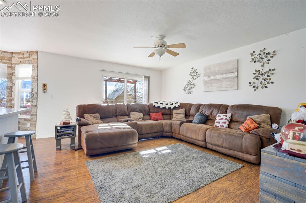 Image 18 of 27: Living room with dark wood-style flooring, a ceiling fan, and a textured ce