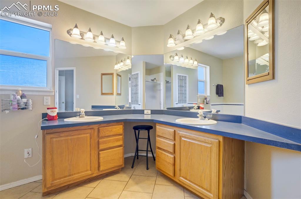 Image 19 of 27: Full bathroom with double vanity, light tile patterned flooring, and a walk