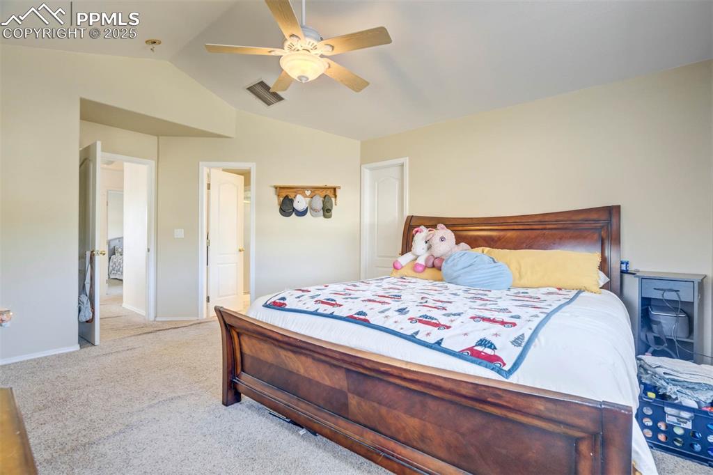 Image 23 of 27: Carpeted bedroom featuring vaulted ceiling and ceiling fan