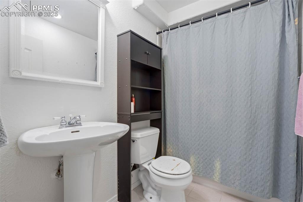 Image 30 of 39: Bathroom featuring light tile patterned flooring, a shower with shower curt