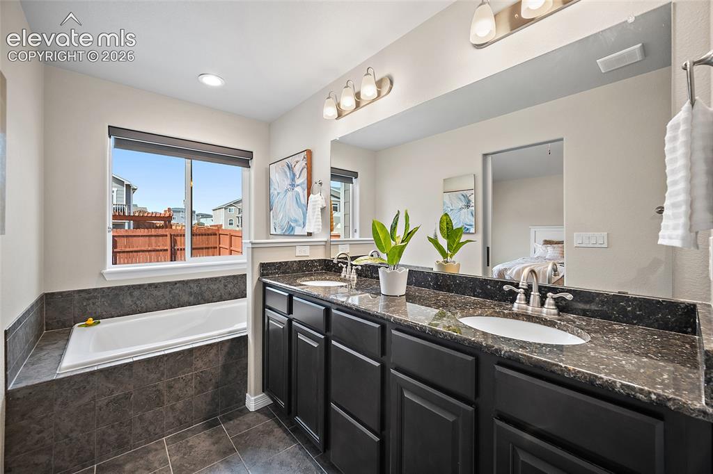Image 12 of 29: Dual vanity with dark cabinetry, integrated oval sinks, and speckled counte