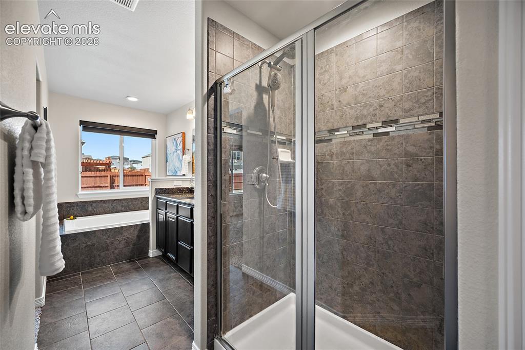 Image 13 of 29: Walk-in shower with glass enclosure, tiled walls featuring a decorative mos