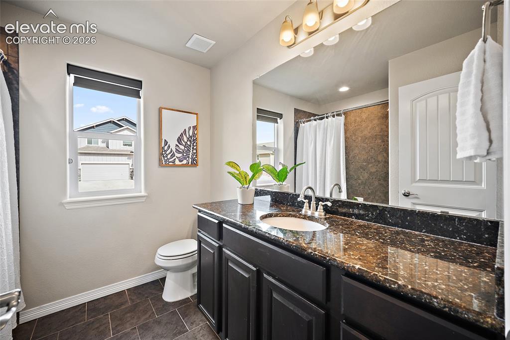 Image 15 of 29: Vanity with a granite countertop, undermount sink, and dark wood-finish cab