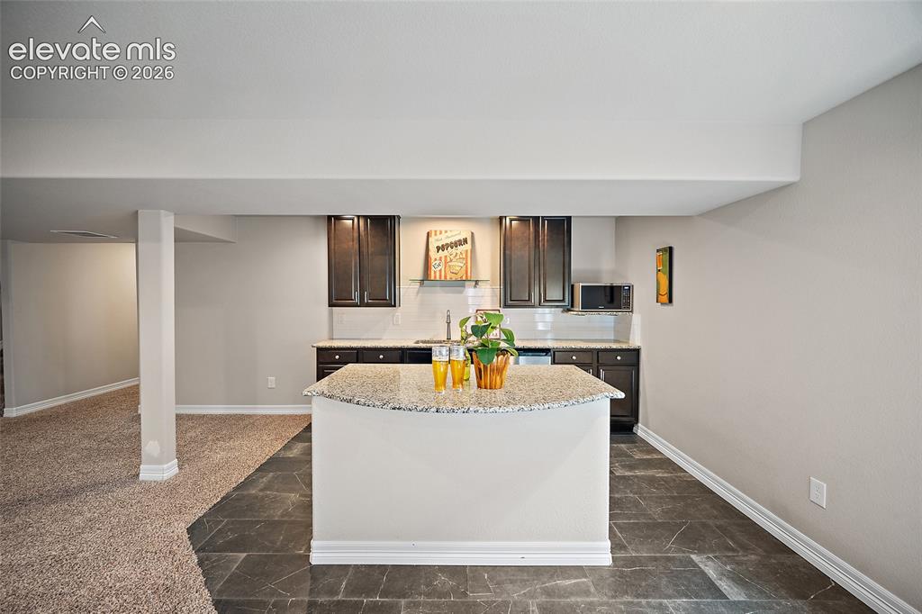 Image 20 of 29: Kitchenette featuring dark wood cabinetry, a light-colored countertop, and