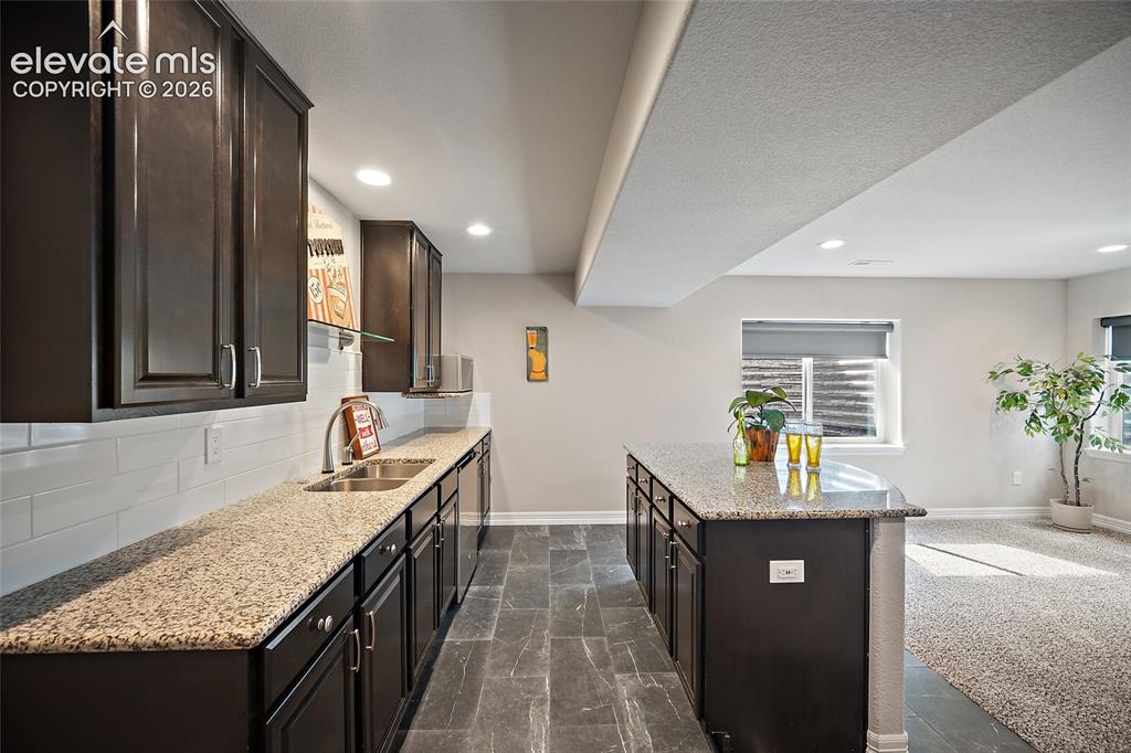 Image 21 of 29: Kitchenette featuring dark wood cabinetry, light-toned countertops, a stain