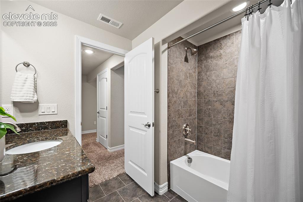 Image 25 of 29: Bathroom featuring a dark wood-finish vanity with a dark speckled counterto