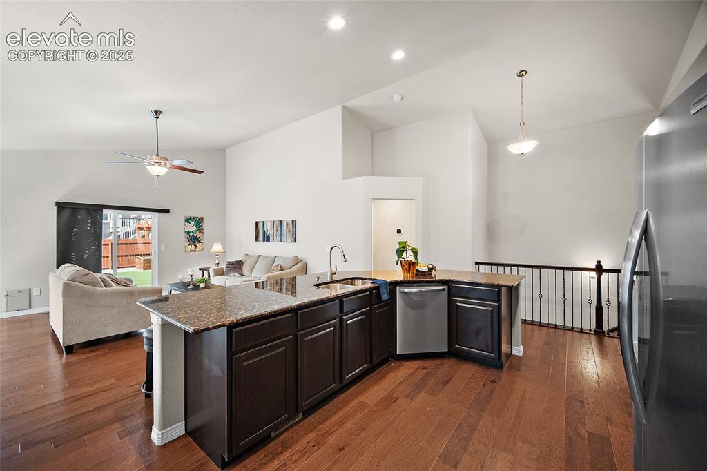 Image 5 of 29: Kitchen island with dark wood-finish cabinetry and stone-look countertop