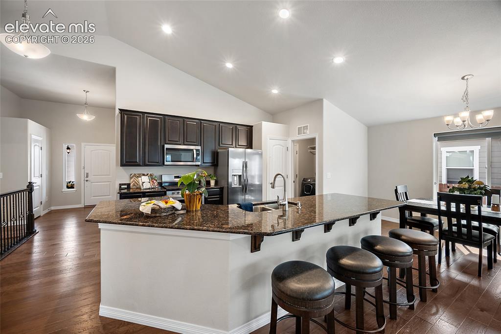 Image 6 of 29: Kitchen featuring dark wood cabinetry, stainless steel appliances, and an e