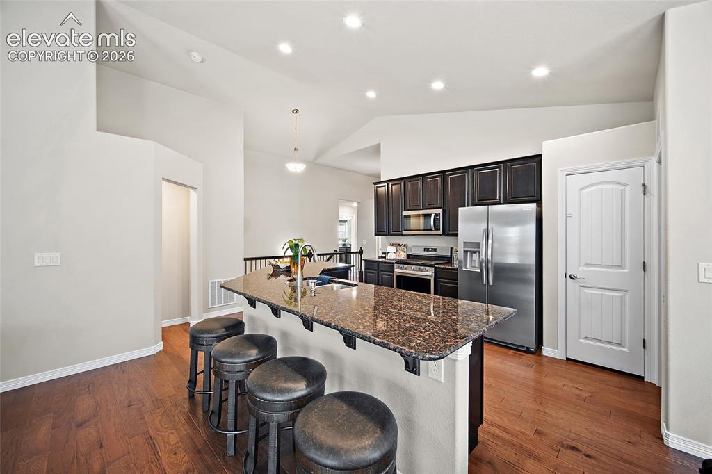 Image 7 of 29: Kitchen with dark wood cabinetry, stainless steel appliances, wood-finish f