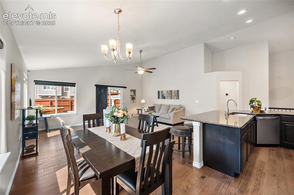 Image 9 of 29: Open-concept living area with wood-finish flooring, vaulted ceilings, and r