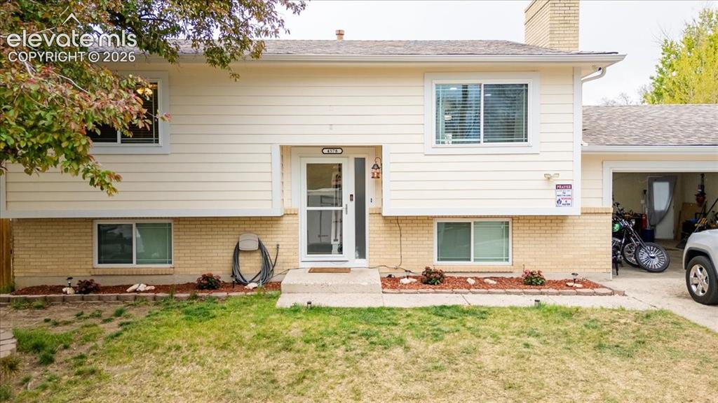 Image 2 of 50: Split-level residence featuring light-colored siding and a brick base