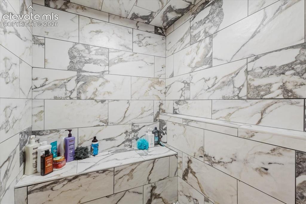 Image 22 of 50: Shower enclosure featuring large format white and gray variegated tiles