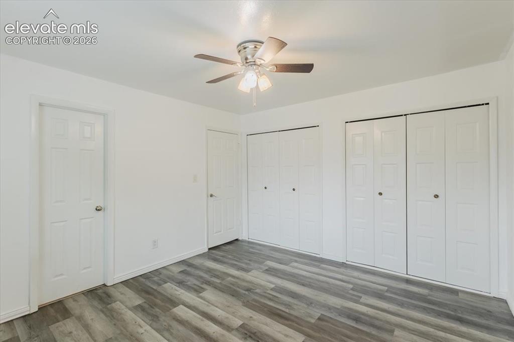 Image 31 of 50: Room featuring wood-finish flooring, a ceiling fan with light kit, and whit