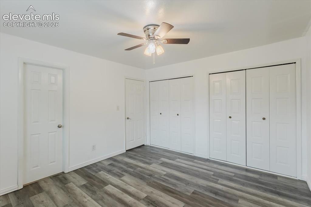 Image 32 of 50: Spacious room featuring wood-finish flooring, bright white walls, two sets
