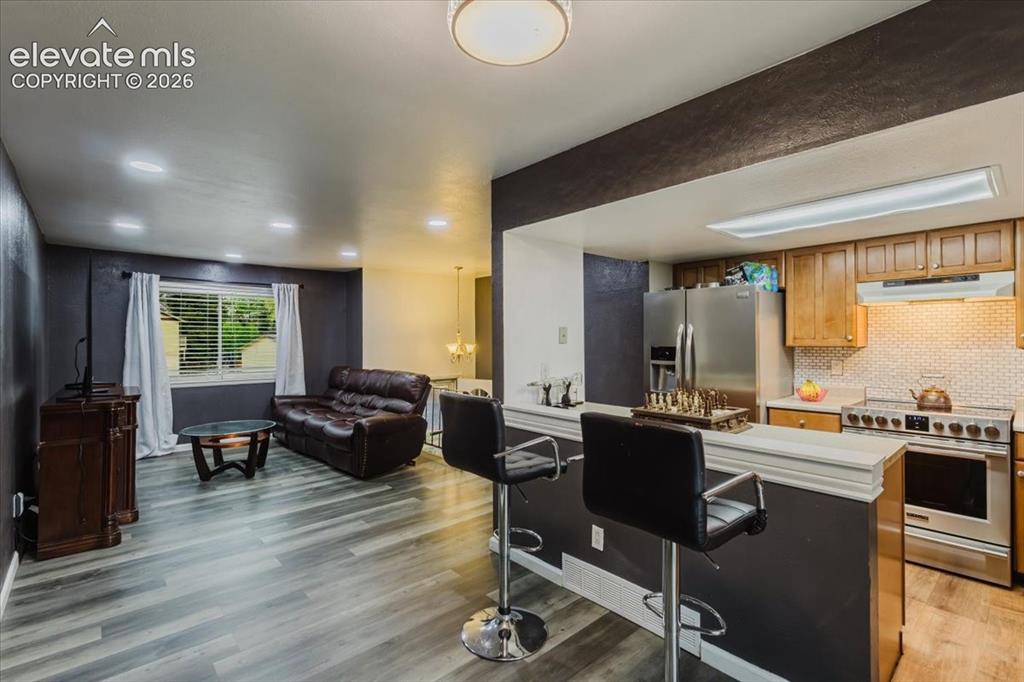 Image 39 of 50: Open-concept living area featuring wood-finish flooring, recessed lighting,