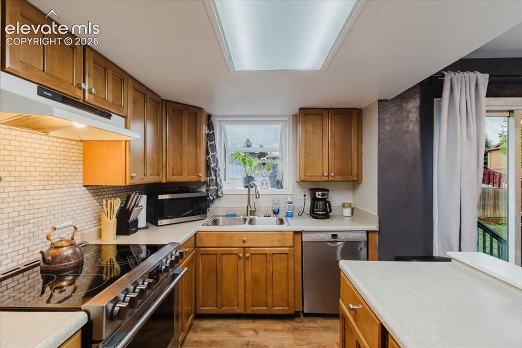 Image 41 of 50: Kitchen featuring wood-finish cabinetry, solid surface countertops, and a s