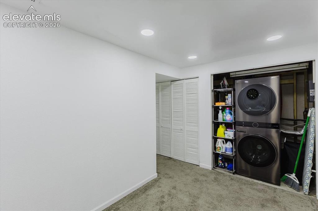 Image 8 of 50: Dedicated laundry area featuring a stacked washer and dryer unit
