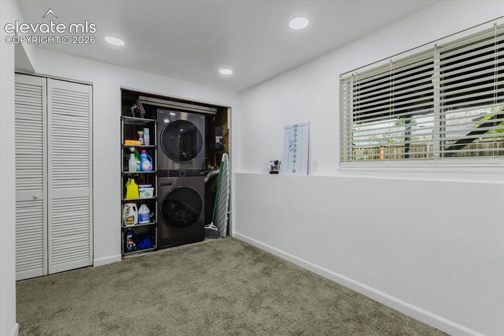 Image 9 of 50: Dedicated laundry area featuring a stacked washer and dryer unit, integrate