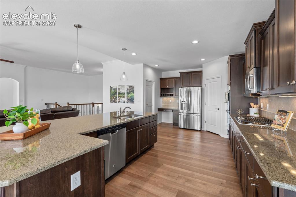 Image 17 of 50: Kitchen featuring wood-finish flooring, dark wood cabinetry, and speckled c