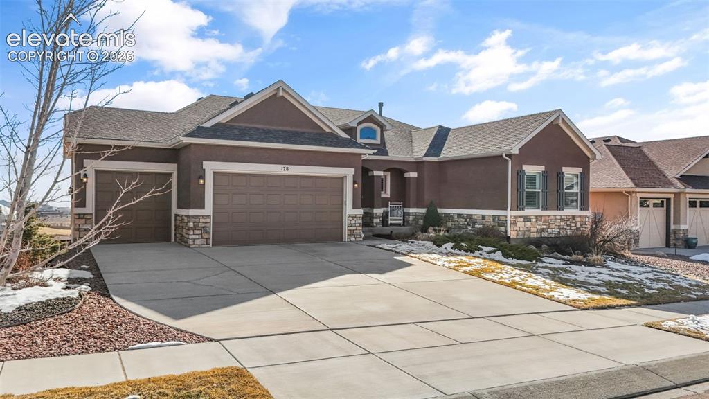Image 2 of 50: Front exterior featuring a brown stucco finish with stone accents and dark 