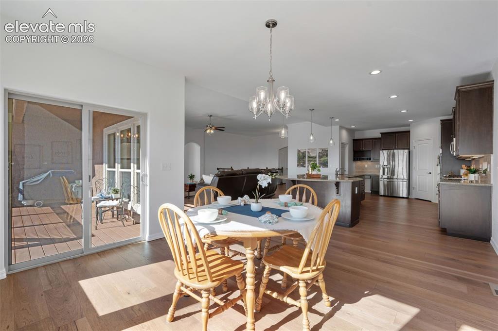 Image 23 of 50: Dining area featuring wood-finish flooring, a modern chandelier, and slidin