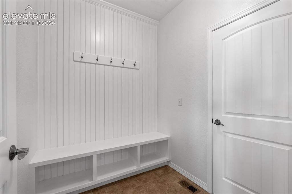 Image 24 of 50: Mudroom area featuring white wainscoting, integrated bench seating with ope