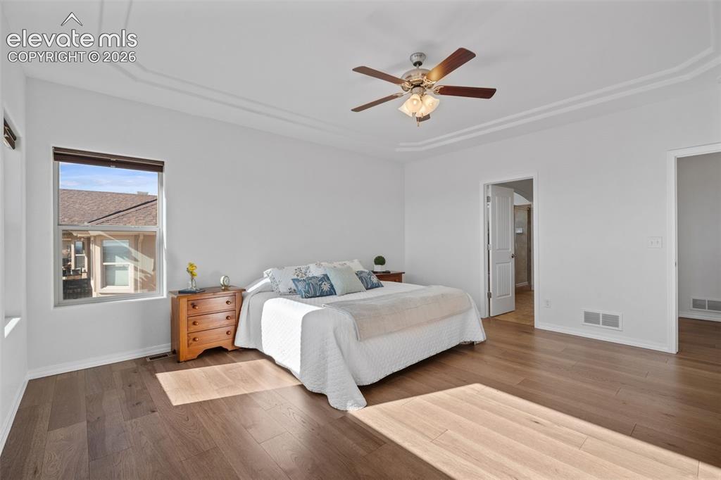 Image 27 of 50: Spacious room featuring wood-finish flooring, a tray ceiling with crown mol