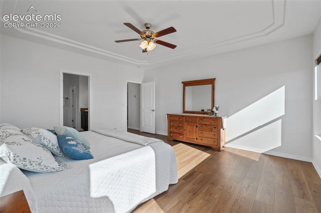 Image 28 of 50: Recessed tray ceiling with crown molding, wood-finish flooring, and ceiling