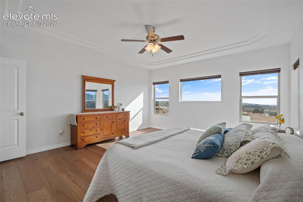 Image 29 of 50: Spacious room featuring tray ceiling details, a ceiling fan with integrated