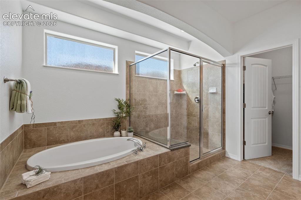 Image 31 of 50: Spacious bathroom featuring a built-in soaking tub and a separate glass-enc