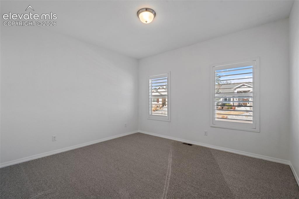 Image 36 of 50: Neutral tone room featuring two windows with white plantation shutters, gra