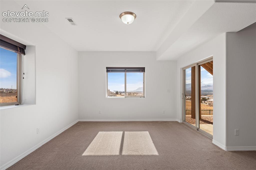 Image 40 of 50: Spacious interior room featuring light-colored carpeting and white walls