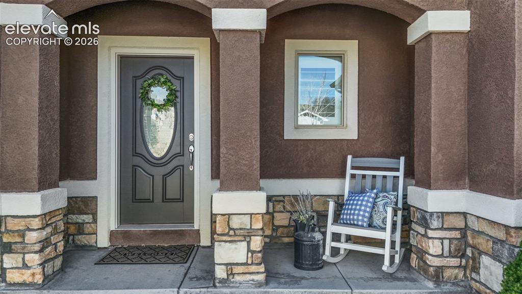 Image 5 of 50: Arched entryway with a dark paneled door featuring an oval glass insert, co