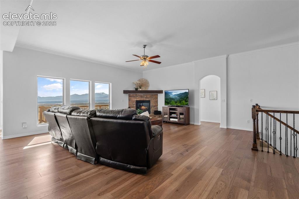 Image 9 of 50: Spacious living area featuring wood-finish flooring, a stone-faced fireplac