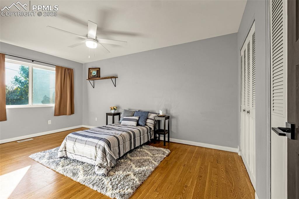 Image 11 of 33: Bedroom with light wood finished floors, two closets, and ceiling fan