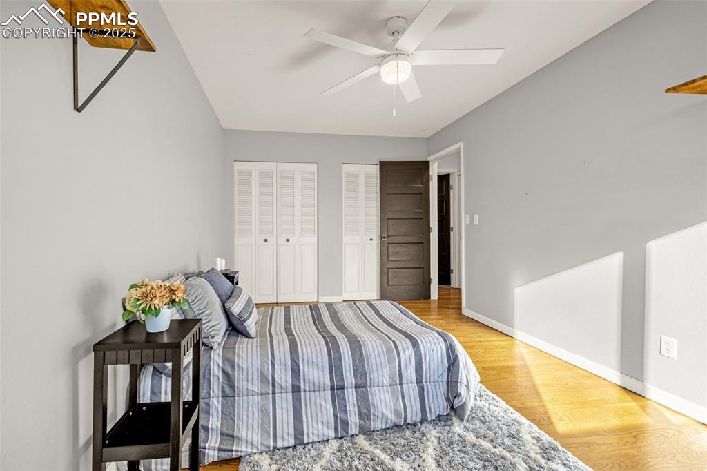 Image 12 of 33: Bedroom with light wood finished floors, multiple closets, and ceiling fan