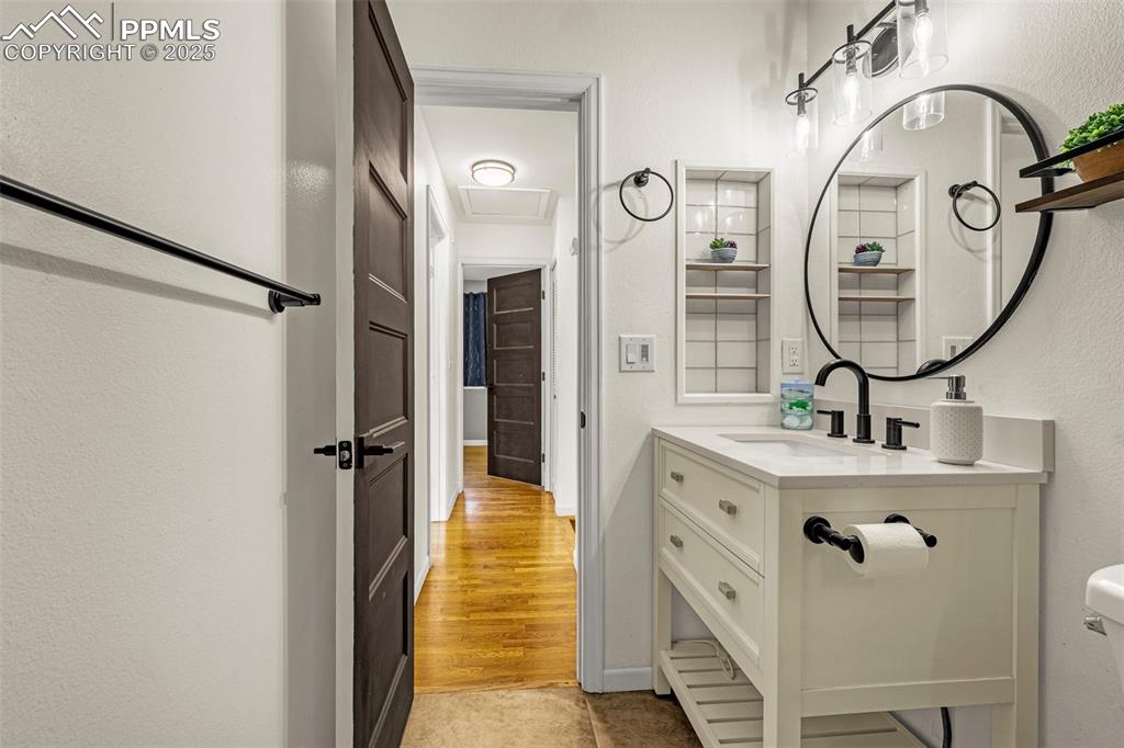 Image 16 of 33: Half bath with vanity, a textured wall, and light wood-style flooring