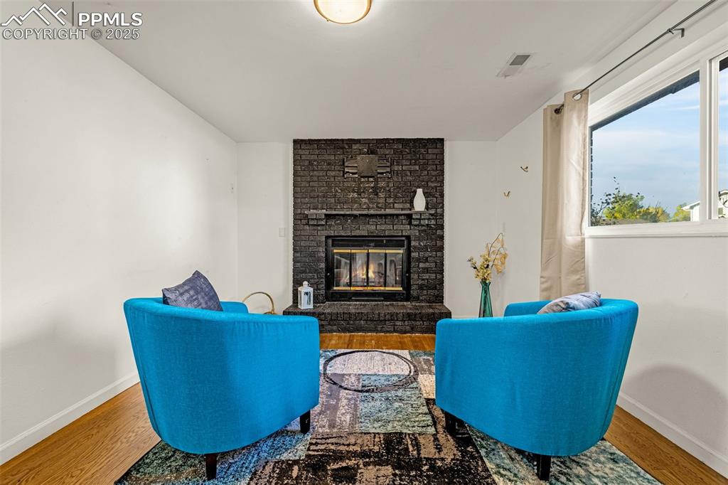 Image 18 of 33: Sitting room featuring wood finished floors and a brick fireplace