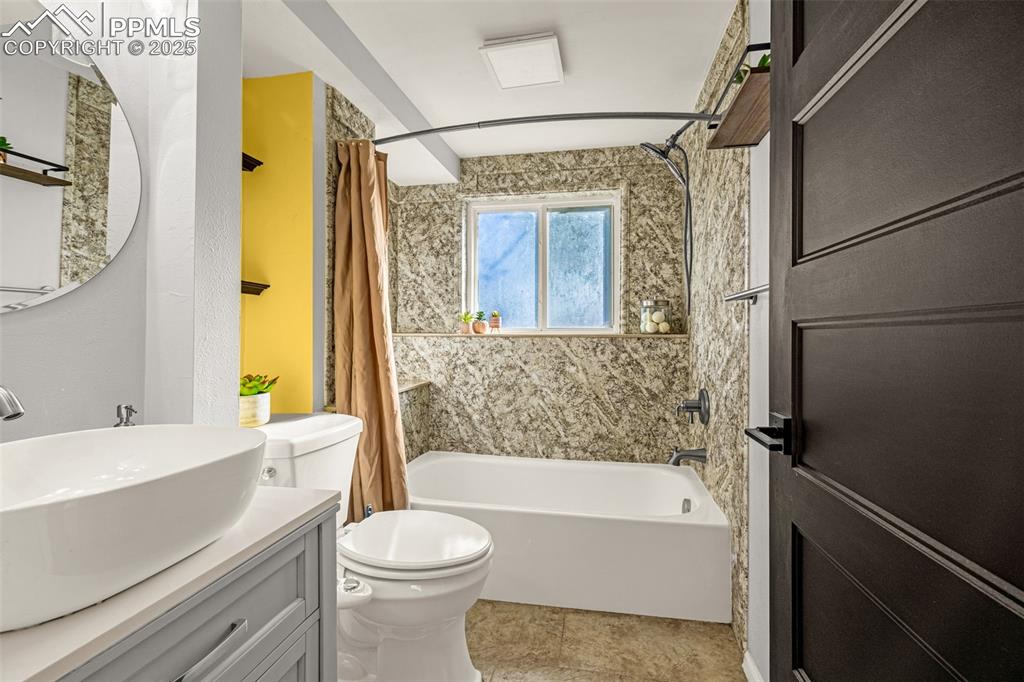 Image 22 of 33: Bathroom with shower / bathtub combination with curtain and vanity