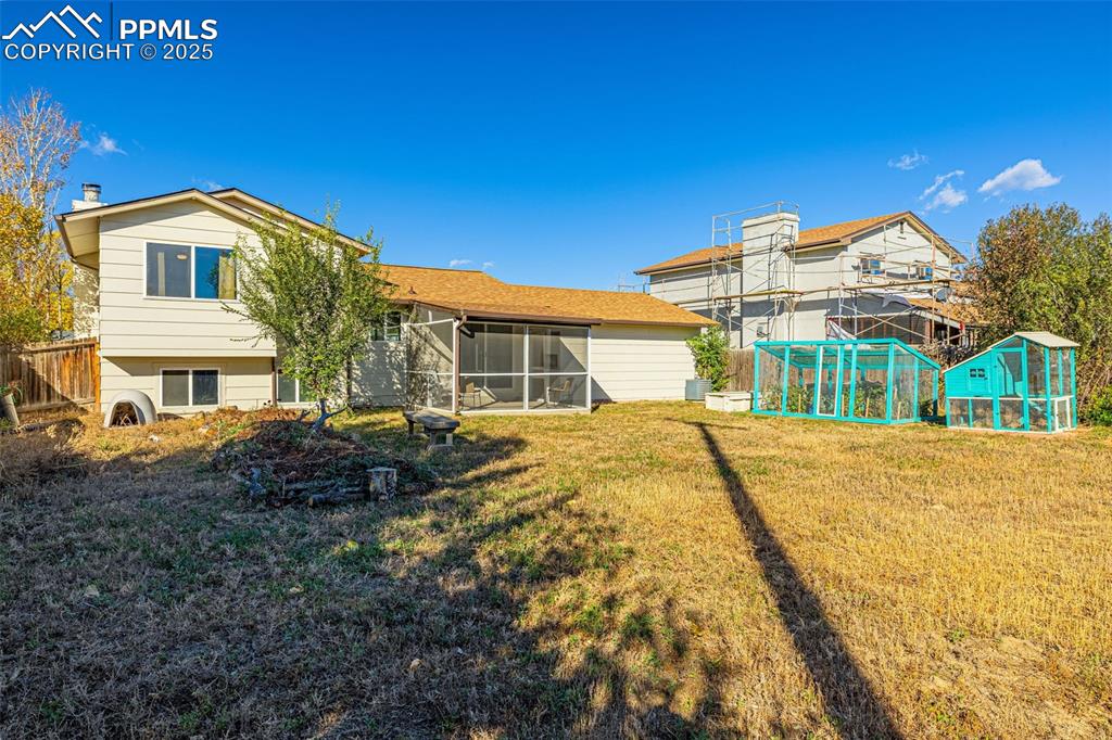 Image 25 of 33: Rear view of property featuring a sunroom, a chimney, an outbuilding, and e