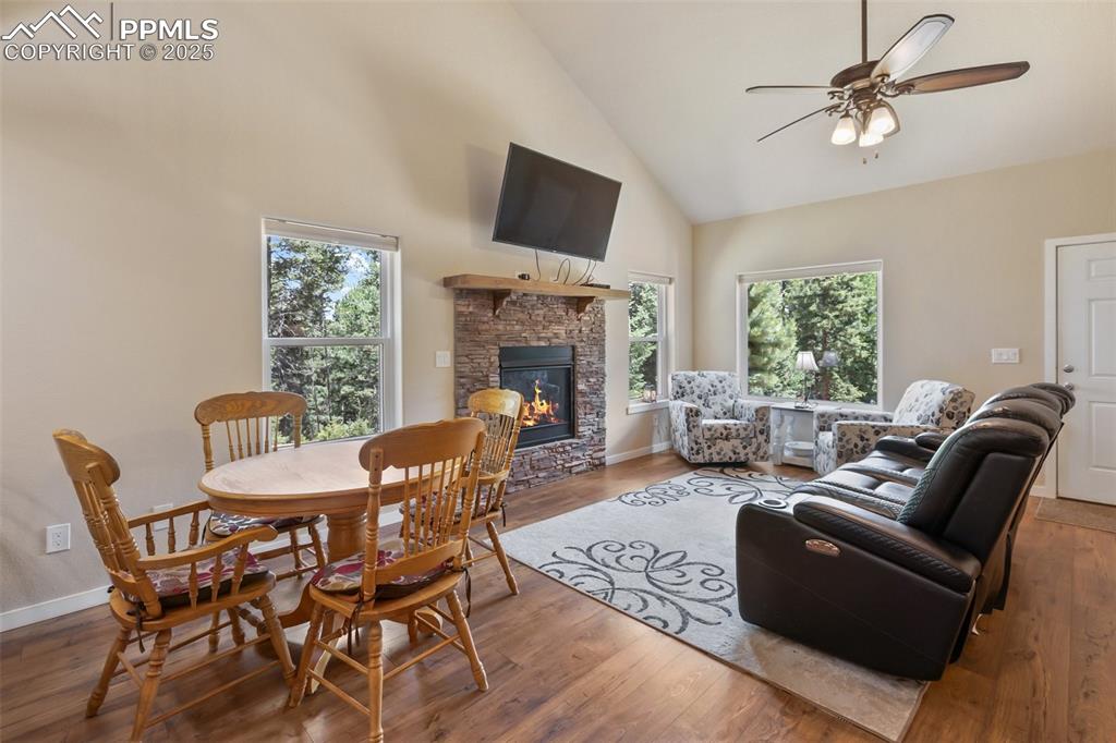 Image 15 of 46: Living area featuring high vaulted ceiling, a stone fireplace, ceiling fan,
